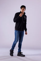 Person wearing a black jacket, blue jeans, and black shoes on a white background