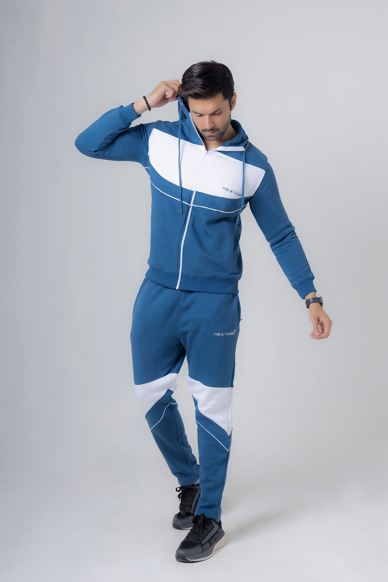 Person wearing a blue and white tracksuit on a gray background
