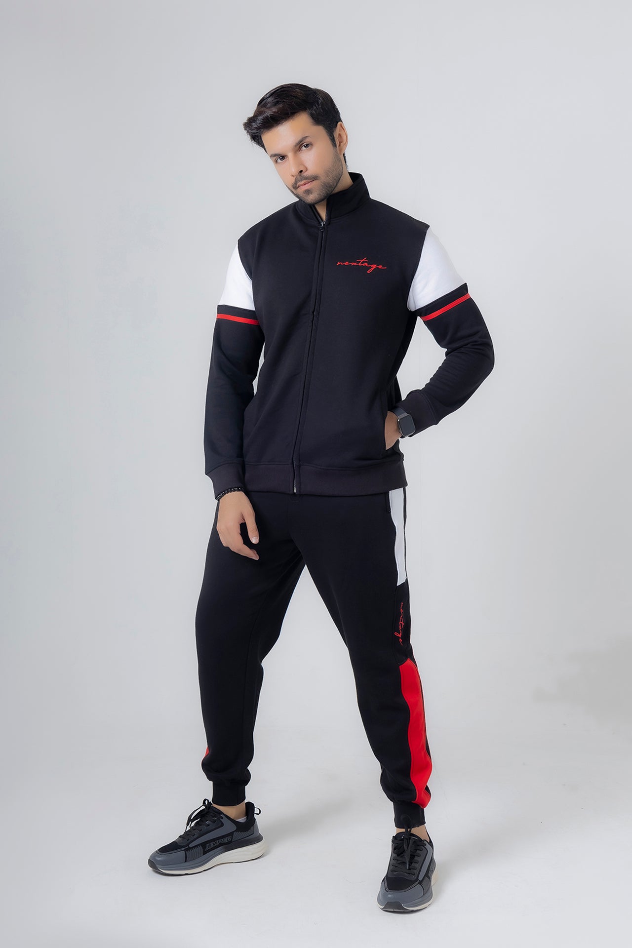 Man wearing a black and white tracksuit with red accents on a white background