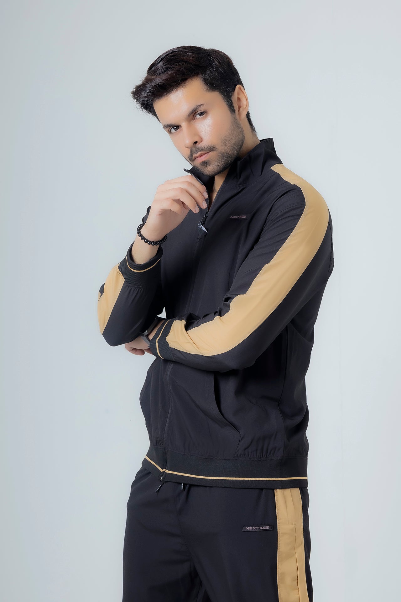 Man wearing a black and beige tracksuit against a white background