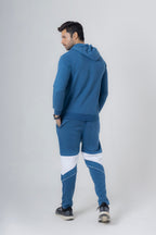 Man wearing a blue tracksuit with white accents on a light gray background