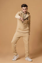 Nextage Model wearing a beige tracksuit with a brand logo on a brown background