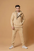 Nextage Man wearing a beige tracksuit with a logo on a oatmeal background