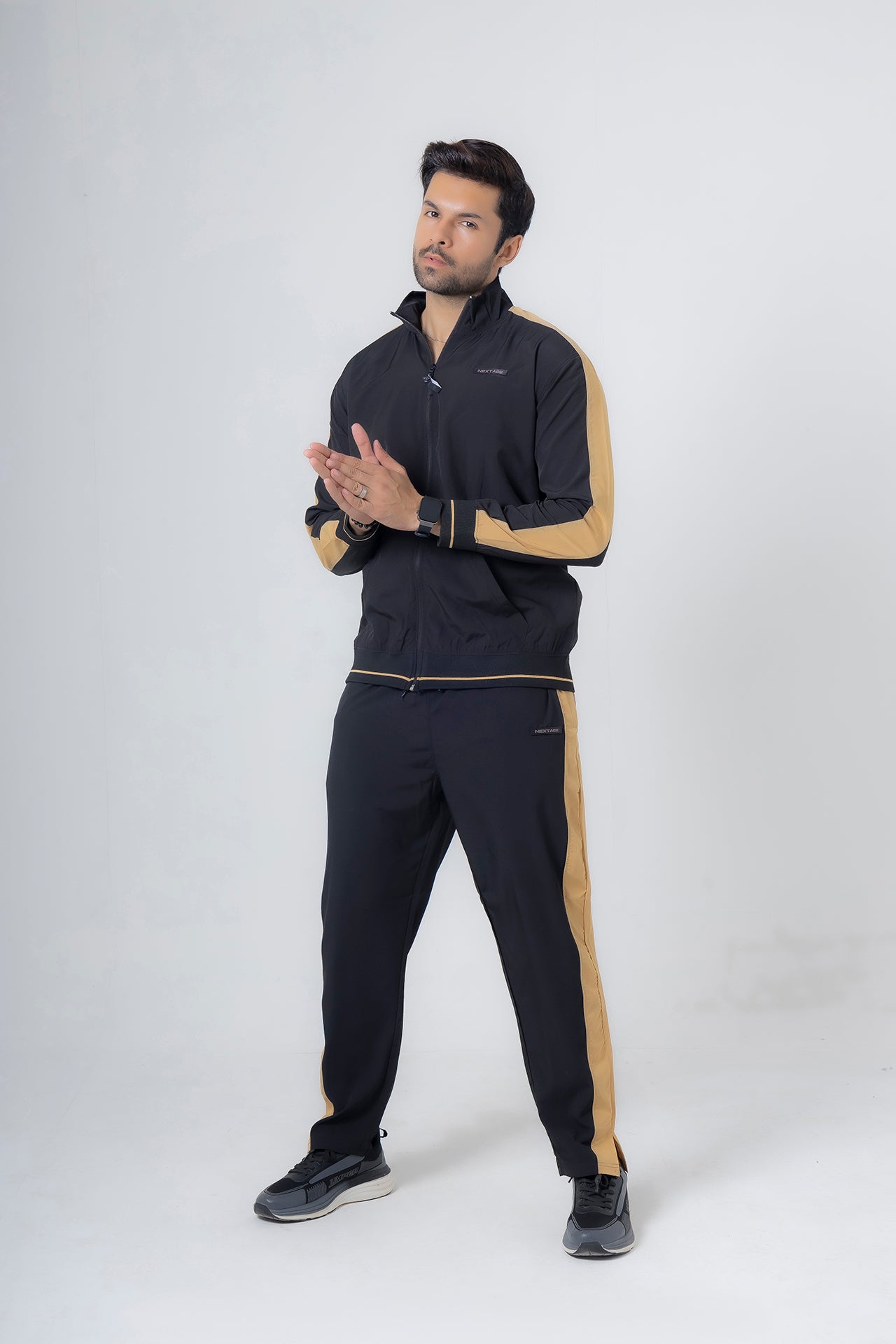 Man wearing a black and gold tracksuit on a white background