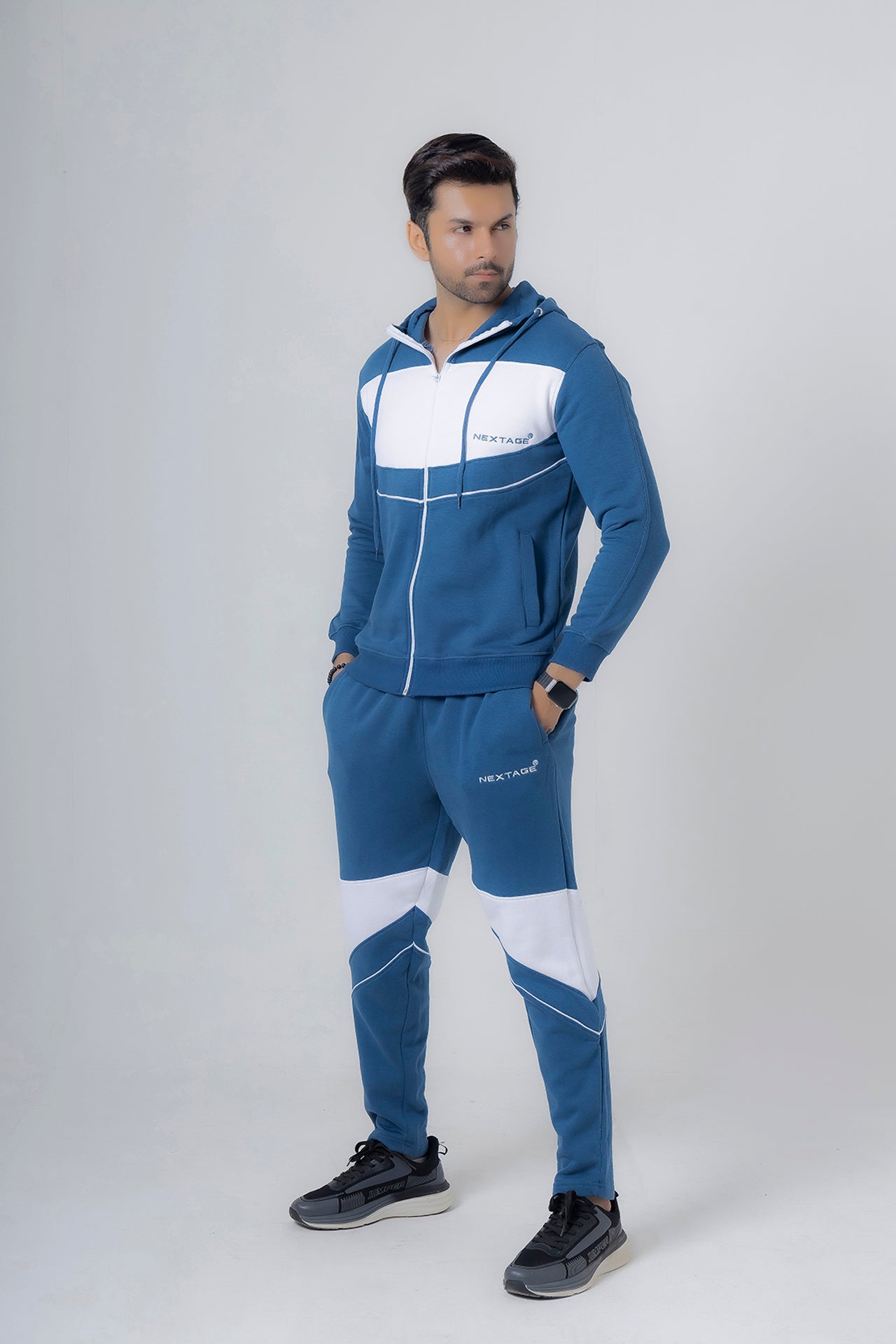 Man wearing a blue and white tracksuit on a gray background
