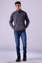 Man wearing a gray jacket, blue jeans, and black boots on a white background