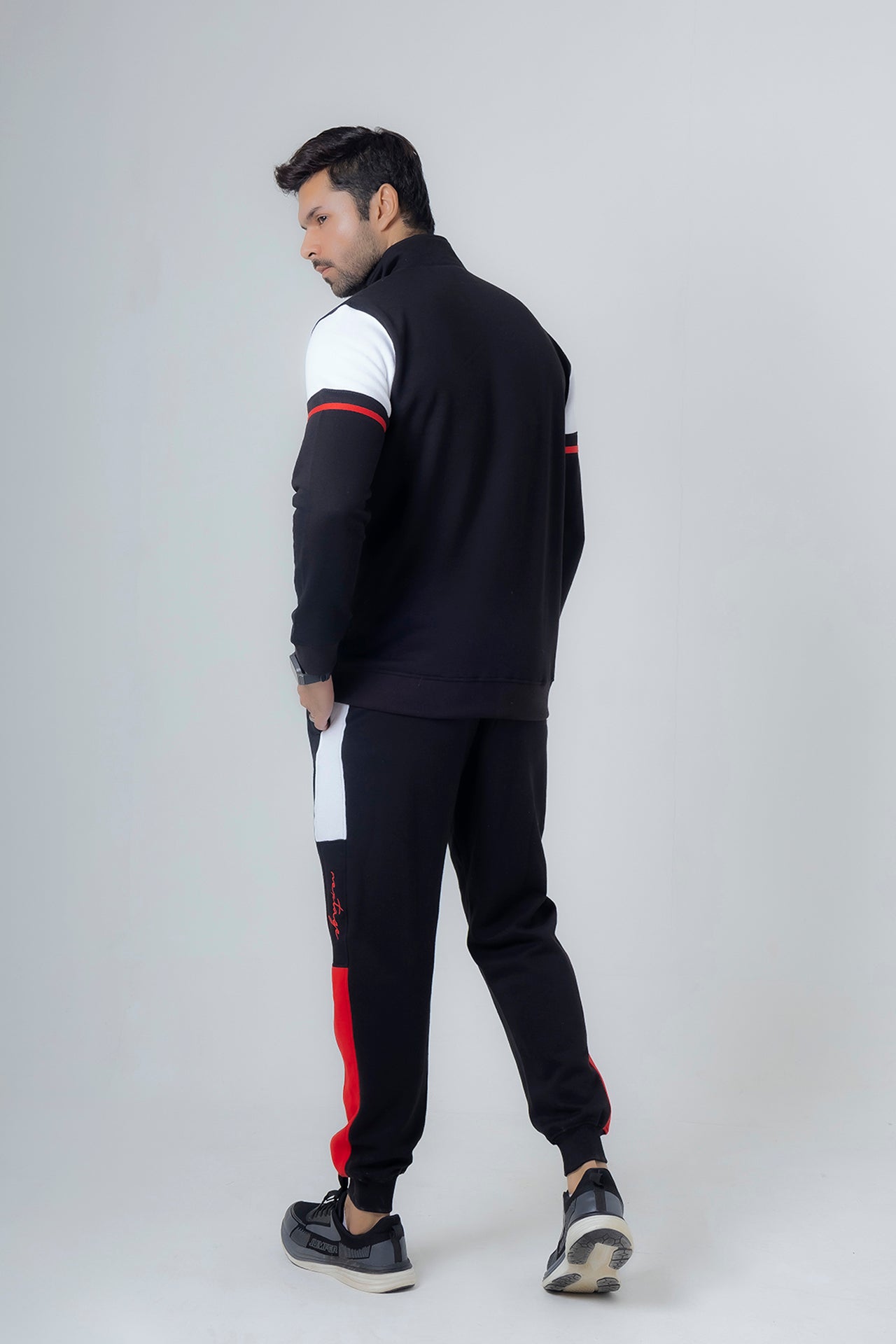 Man wearing a black and white tracksuit with red accents on a white background