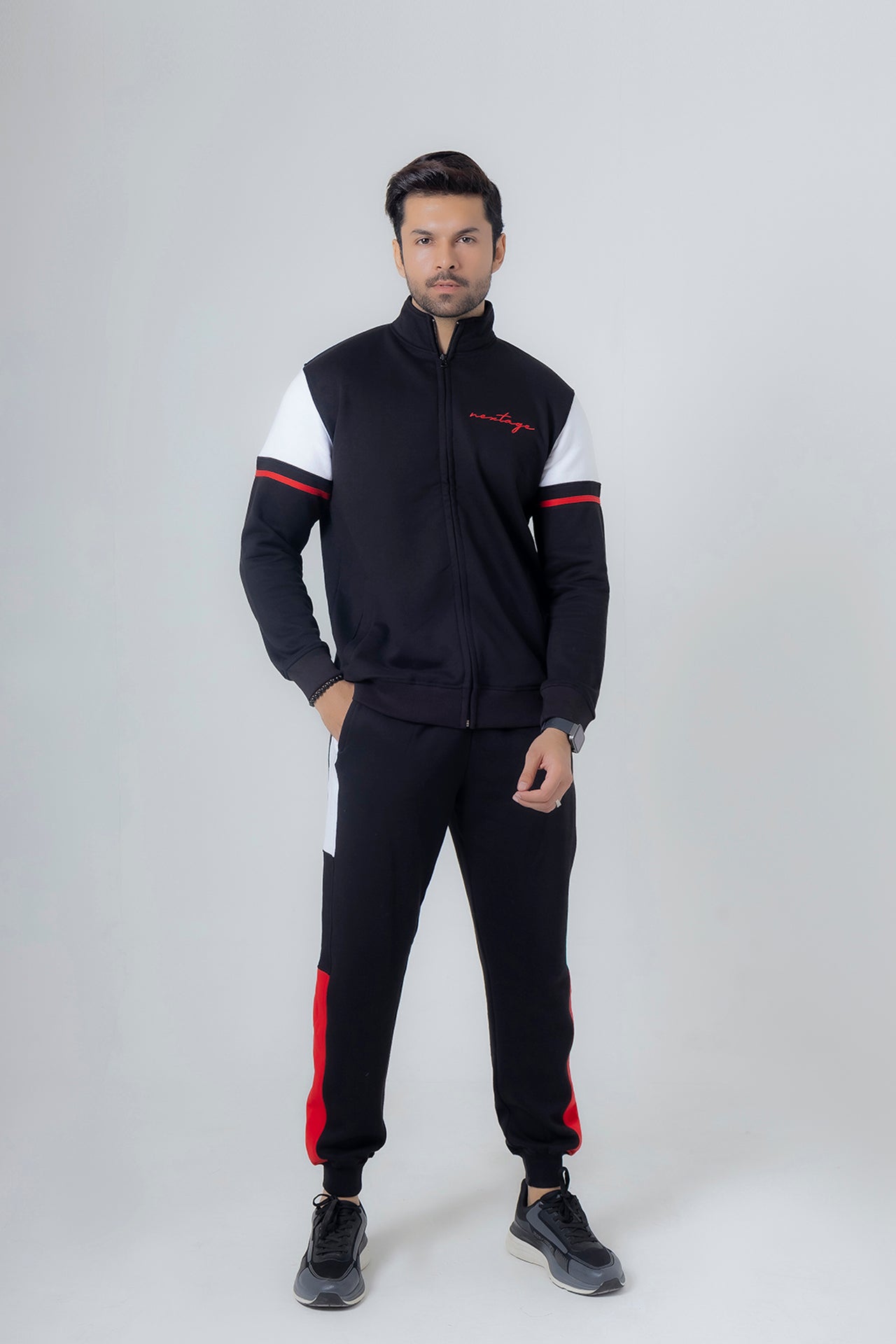 Man wearing a black and white tracksuit with red accents on a white background