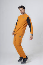 Man wearing a mustard yellow tracksuit with black sleeves on a white background