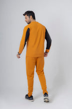 Man wearing a mustard yellow and black tracksuit on a white background