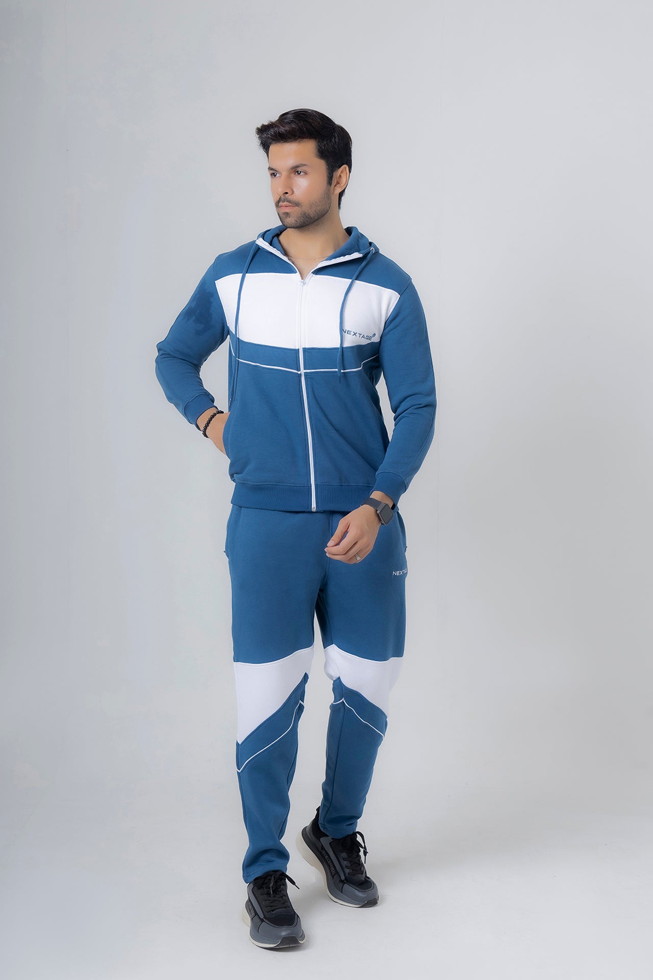 Man wearing a blue and white tracksuit on a gray background
