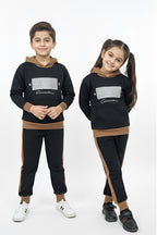 Two children wearing matching black outfits with brown accents on a white background