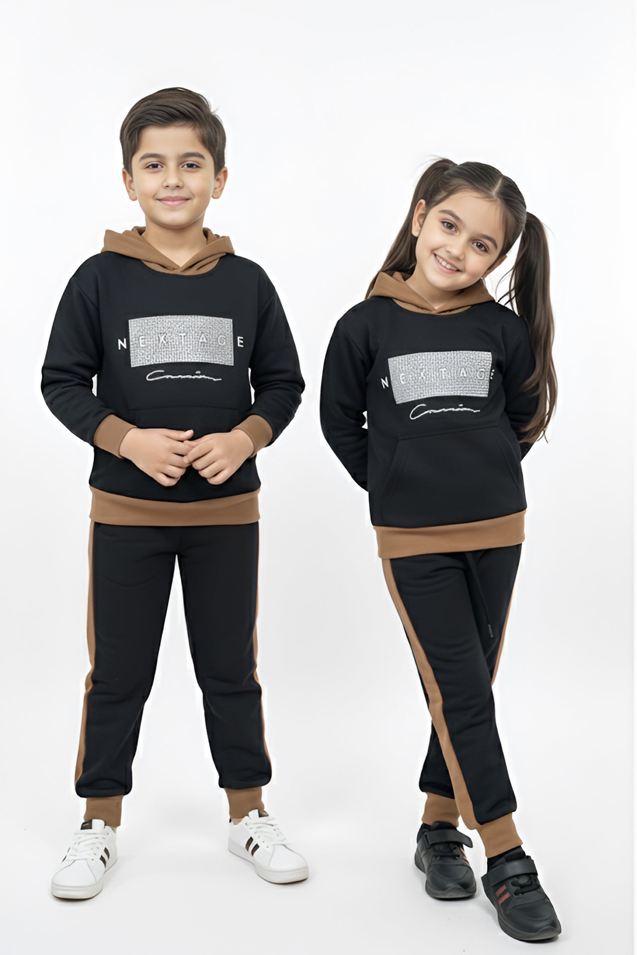 Two children wearing matching black outfits with brown accents on a white background