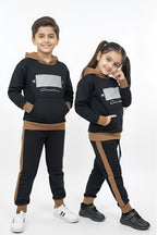 Two children wearing matching black and brown tracksuits on a white background