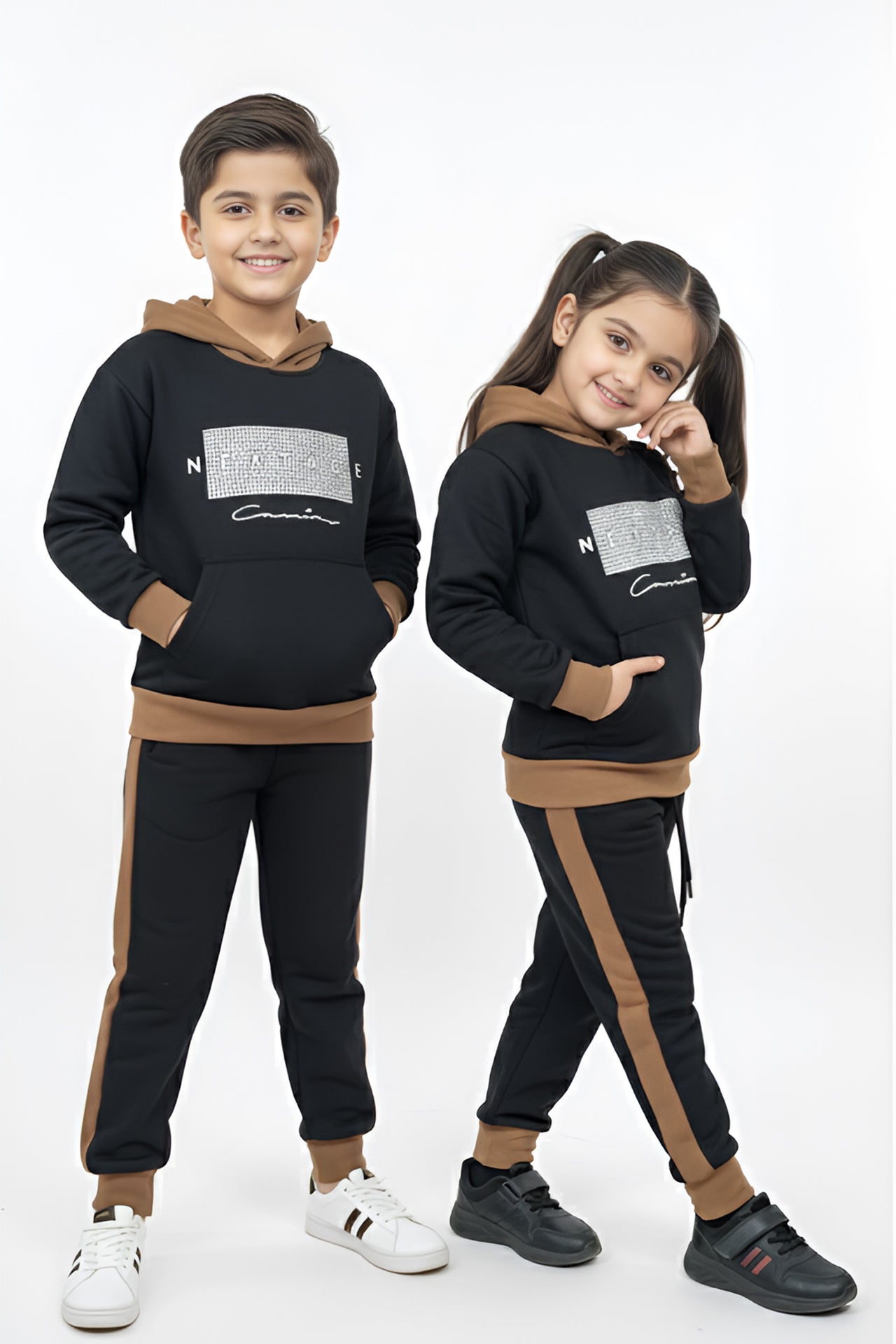 Two children wearing matching black and brown tracksuits on a white background