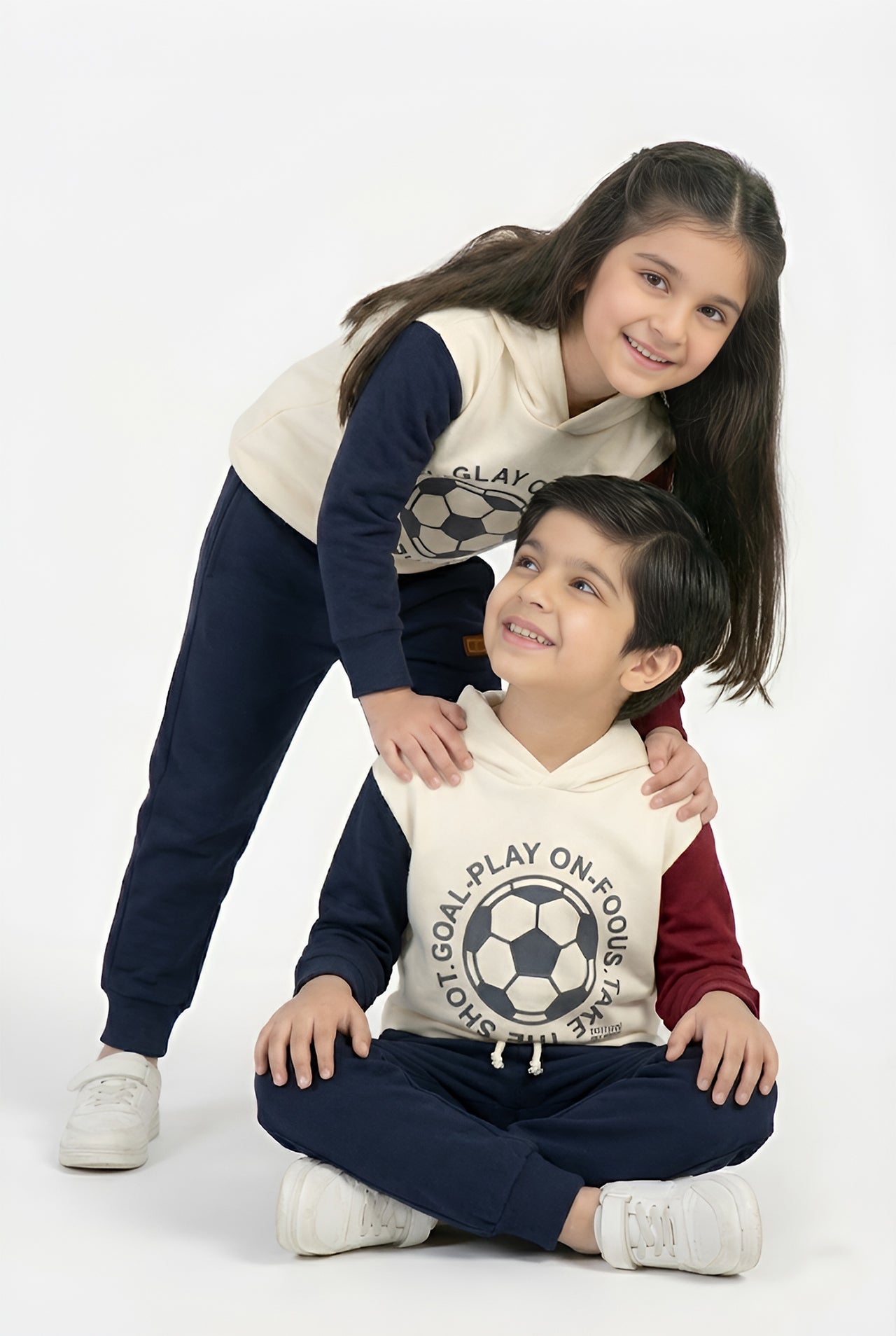 Two children wearing matching soccer-themed hoodies on a white background