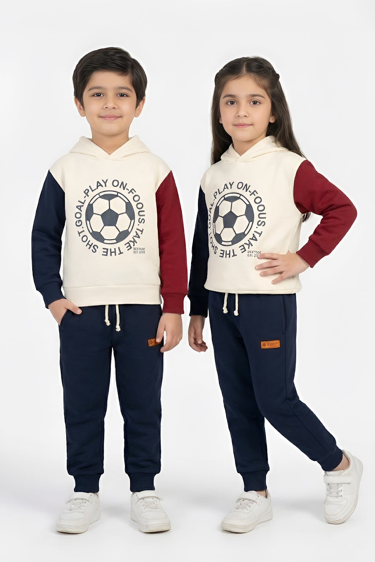 Two children wearing matching soccer-themed outfits on a white background