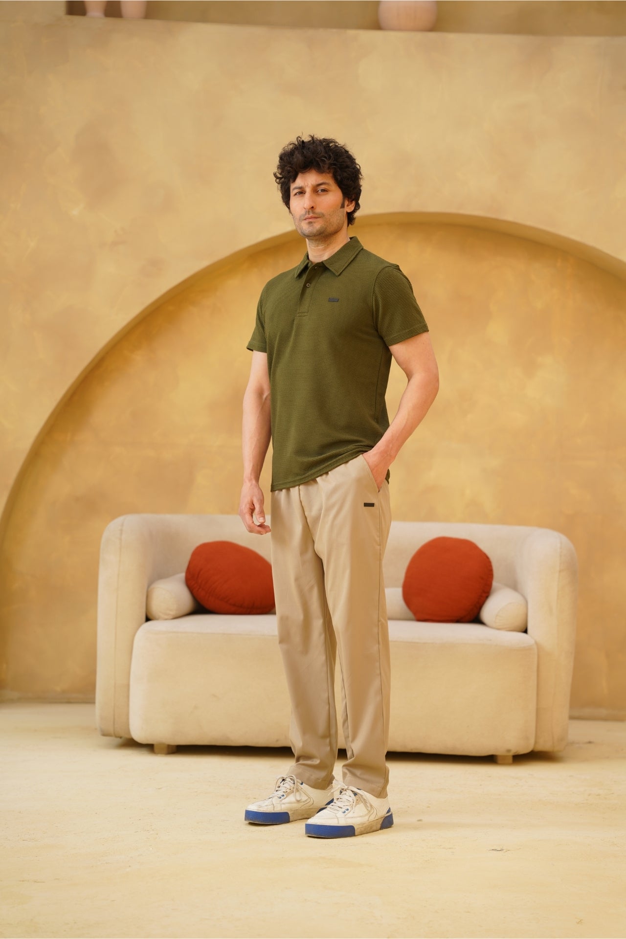 Front view of man wearing olive textured polo shirt with beige smart trousers by Nextage